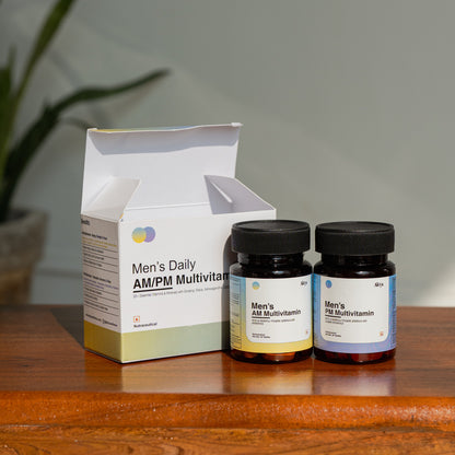 Two bottles of Men's Daily AM/PM Multivitamin on a wooden surface with a box in the background.